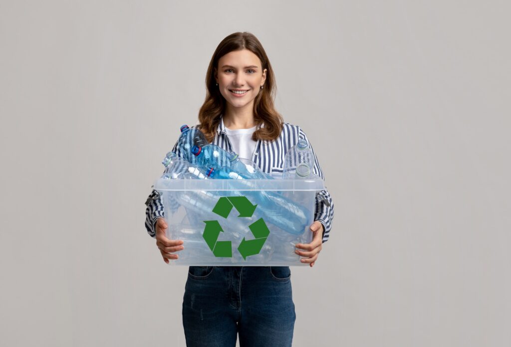 Waste Reuse. Cheerful Young Woman Carrying Container With Plastic Bottles For Recycling