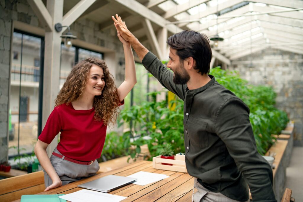 Young man and woman sitting indoors in green office, business meeting concept